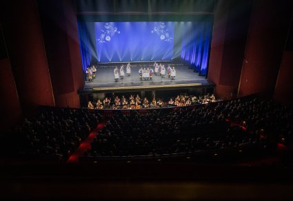 Na zdjęciu widoczna część publiczności, Orkiestron a w nim Artyści Orkiestry wraz z Dyrygentem, na scenie Artyści w kostiumach kaszubskich podczas wykonywania choreografii tanecznej