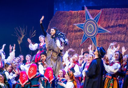 Scena grupowa Artystów, na środku postać Turonia machającego do publiczności