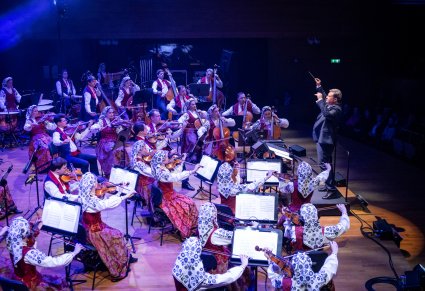 Widok na orkiestrę w kostiumach wilanowskich wraz z Dyrektorem zespołu "Mazowsze" zwrócony w stronę Muzyków