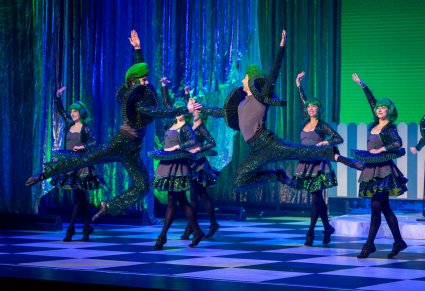 Grupa Artystów odgrywająca role Kół w zielonych kostiumach wykonująca choreografię taneczną na scenie