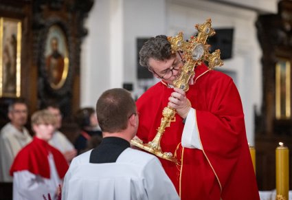 Duchowny w trakcie Odprawiania Mszy Świętej i uszanowanie złotego Krzyża