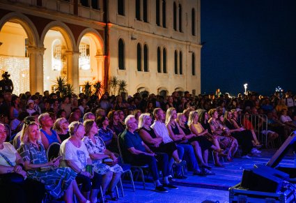 Publiczność na widowni plenerowej w tle oświetlony mur budynku