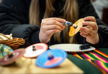 Zbliżenie na malowanie drewnianego bączka przez uczestniczkę warsztatów