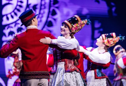 Zbliżenie na parę Artystów w kostiumach kurpiowskich podczas wykonywania choreografii tanecznej na scenie