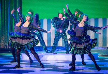 Grupa Artystów odgrywających role kół w zielonych kostiumach wykonujący choreografię taneczną