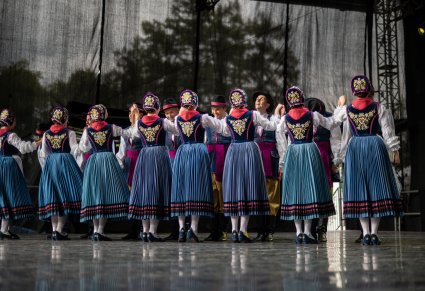 Artyści w kostiumach kaszubskich na scenie wykonujący choreografię taneczną