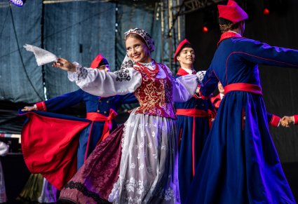 Artyści na scenie w kostiumach wilanowskich, Artystka macha białą chusteczką w kierunku publiczności