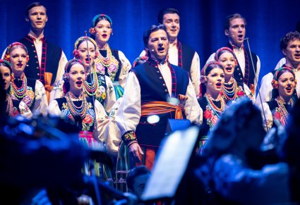 Zbliżenie na solistę chóru podczas koncertu z widocznych chórem w tle