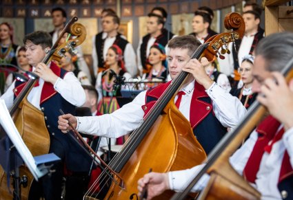 Zbliżenie na artystów orkiestry grających na kontrabasach