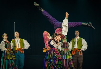 Na pierwszym planie para Artystów w kostiumach opoczyńskich w trakcie wykonywania imponującego partnerowania, w tle pozostałe pary Artystów