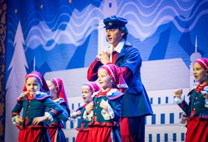 Artysta w kostiumie kujawskim wraz z dziewczynkami również w kostiumach kujawskich wykonujący wspólną choreografię