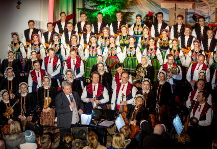 Dyrygent przemawiający po koncercie, widocznych chór i orkiestra