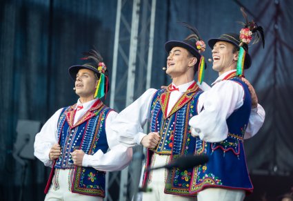 Zbliżenie na trzech Artystów w kostiumach limanowskich w trakcie śpiewu