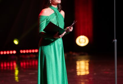 Konferansjerka w długiej, zielonej sukni na scenie