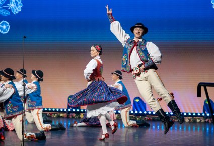 Na scenie grupa Artystów w kostiumach szczawnickich w trakcie wykonywania choreografii tanecznej