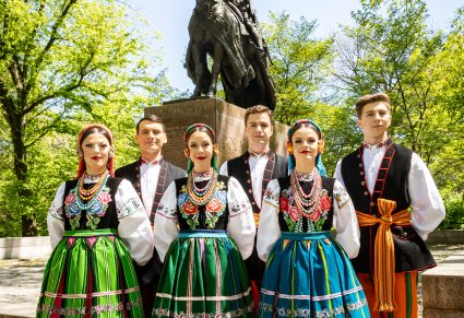 3 Pary Artystów w kostiumach łowickich przed pomnikiem króla Jagiełły