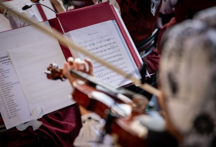 Zbliżenie na pulpit z nutami, a także muzyka grającego na instrumencie smyczkowym