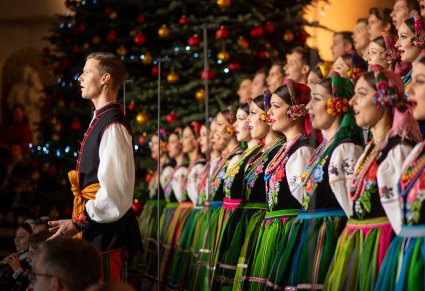 Na pierwszym planie śpiewający solista w kostiumie łowickim, w tle Artyści Chóru
