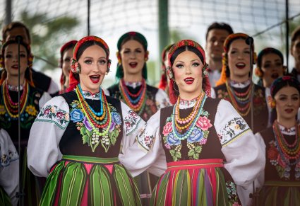 Na pierwszym planie dwie Solistki a w tle reszta część Artystów Chóru w kostiumach łowickich