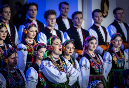 Zbliżenie na solistkę chóru podczas koncertu z widocznych chórem w tle