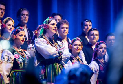 Zbliżenie na solistkę chóru podczas koncertu z widocznych chórem w tle