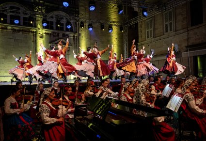 Na pierwszym planie Orkiestra a wyżej na scenie Artyści w kontuszach wykonujący choreografię taneczną