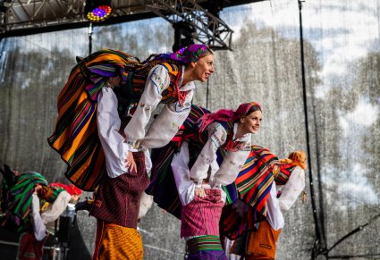 Trzy pary Artystów na scenie w kostiumach opoczyńskich wykonujący choreografię taneczną