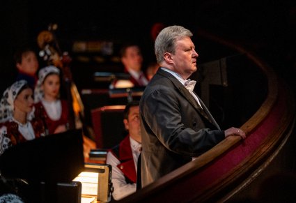 Zbliżenie na Dyrektora zespołu w tle część Orkiestry w kostiumach wilanowskich