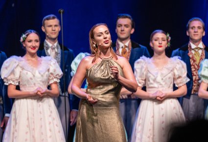 Artyści na scenie wraz z Solistą, która ma złotą sukienkę