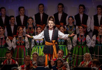 Zbliżenie na solistę chóru podczas koncertu z widocznych chórem w tle