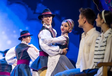 Para Artystów w kostiumach kaszubskich podczas wykonywania choreografii tanecznej, w prawym rogu widoczna Agnieszka z Tomkiem (główni bohaterowie spektaklu)