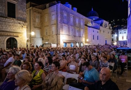 Widok na publiczność pod gołym niebem a w tle budynki w Chorwackim stylu
