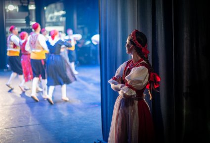 Artystka w kostiumie jurgowskim spoglądająca na scenę zza kotary