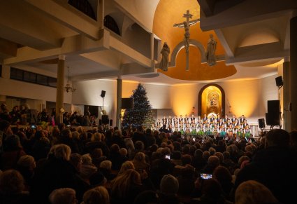 Widok na publiczność koncertu kolęd i pastorałek w kościele w Grodzisku Maz. przed ołtarzem Artyści Chóru w kostiumach łowickich
