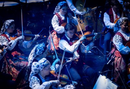 Zbliżenie na artystów orkiestry grających na instrumentach smyczkowcyh