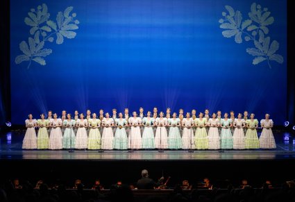 Na scenie Artyści chóru w kostiumach stylowych z końca XIX w. w trakcie śpiewu