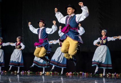 Artyści na scenie w kostiumach kaszubskich wykonujący choreografię taneczną