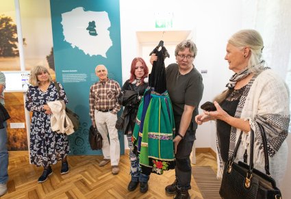 Odwiedzajacy Centrum Folkloru Polskiego "Karolin", podczas sprawdzania wagi kostiumu łowickiego dla dziewczynki