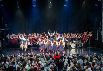Na scenie Artyści Baletu w kostiumach szczawnickich w trakcie wykonywania choreografii tanecznej, w tle Orkiestra w kostiumach wilanowskich