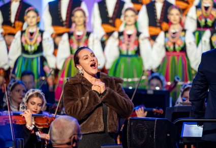 Zbliżenie na solistkę podczas koncertu, w tle widoczna orkiestra i chór