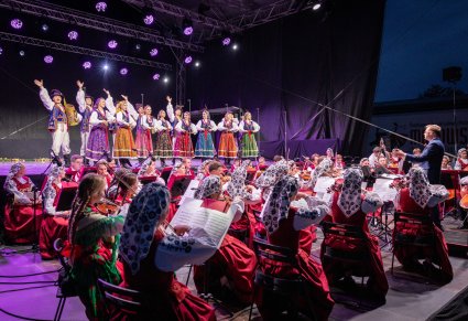 Orkiestra w kostiumach wilanowskich i podhalańskich razem z dyrygentem, w tle artyści baletu w kostiumach limanowskich