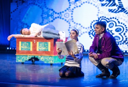 Na pierwszym planie Pan Kajetan i Agnieszka trzymająca w rękach książkę, w tle Tomek leżący na ręcznie malowanej skrzyni