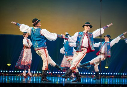 Na pierwszym planie dwóch Tancerzy w kostiumach spiskich podczas wykonywania choreografii tanecznej