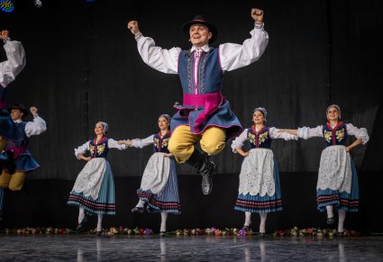 Artyści na scenie w kostiumach kaszubskich wykonujący choreografię taneczną