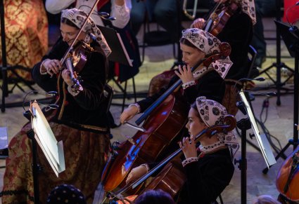 Zbliżenie na osoby grające na wiolonczelach podczas koncertu