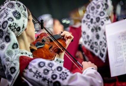 Zbliżenie na Artystkę z Orkiestry w kostiumie wilanowskim, grającą na skrzypcach