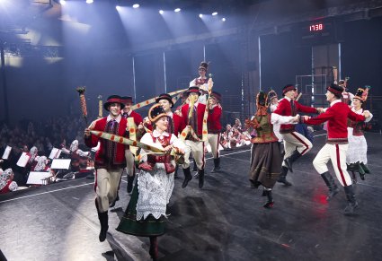 Grupa Artystów w kostiumach kurpiowskich (Kurpie Puszczy Zielonej) w trakcie wykonywania choreografii tanecznej