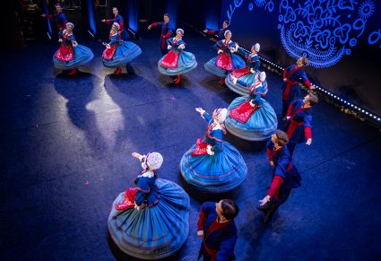 Artyści w kostiumach kujawskich w półokręgu na scenie, tancerki w obrocie