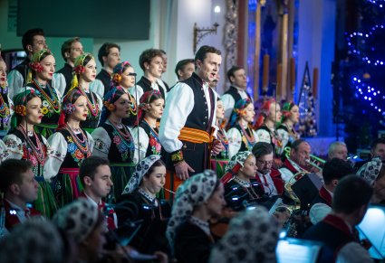 Zbliżenie na solistę chóru podczas koncertu z widocznych chórem i orkiestrą
