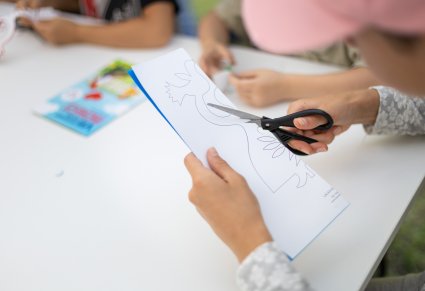 Uczestnicy warsztatów prowadzonych przez Centrum Folkloru Polskiego "Karolin" wycinają wycinankę z papieru